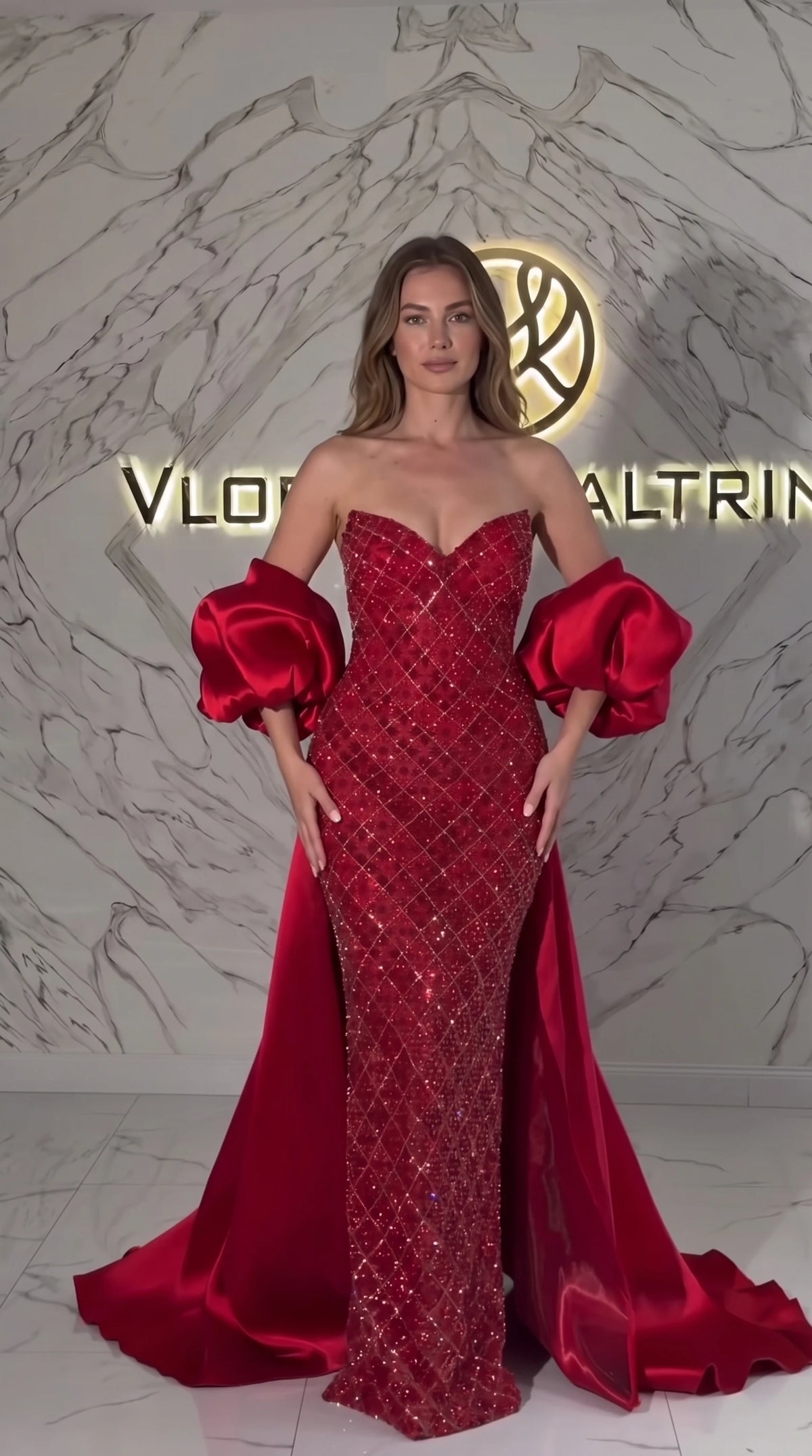 Front view of model wearing Ruby Red strapless sequin mermaid evening gown with satin train and puff sleeves