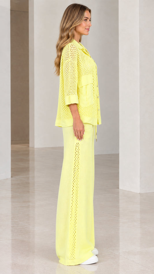 Side profile view of woman wearing light yellow open knit pants set