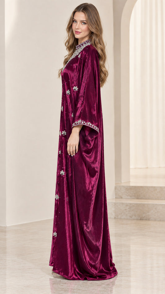 Side profile view of woman modeling flowing burgundy velvet kaftan gown