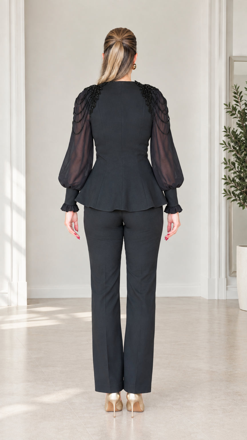 Back view of woman wearing tailored black peplum top and matching trousers