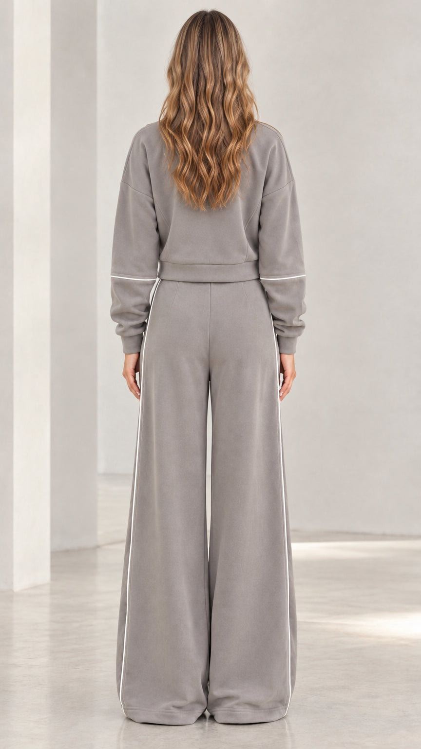 Back view of woman wearing grey two-piece zip jacket and wide leg pants set