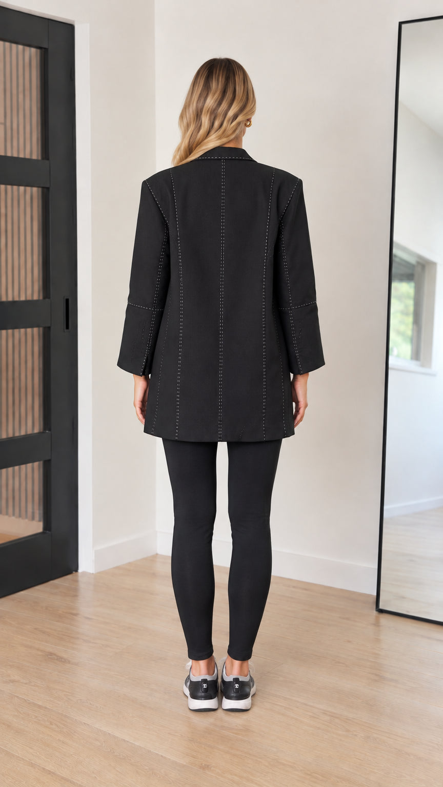 Back view of model showing vertical contrast seam stitching on black blazer