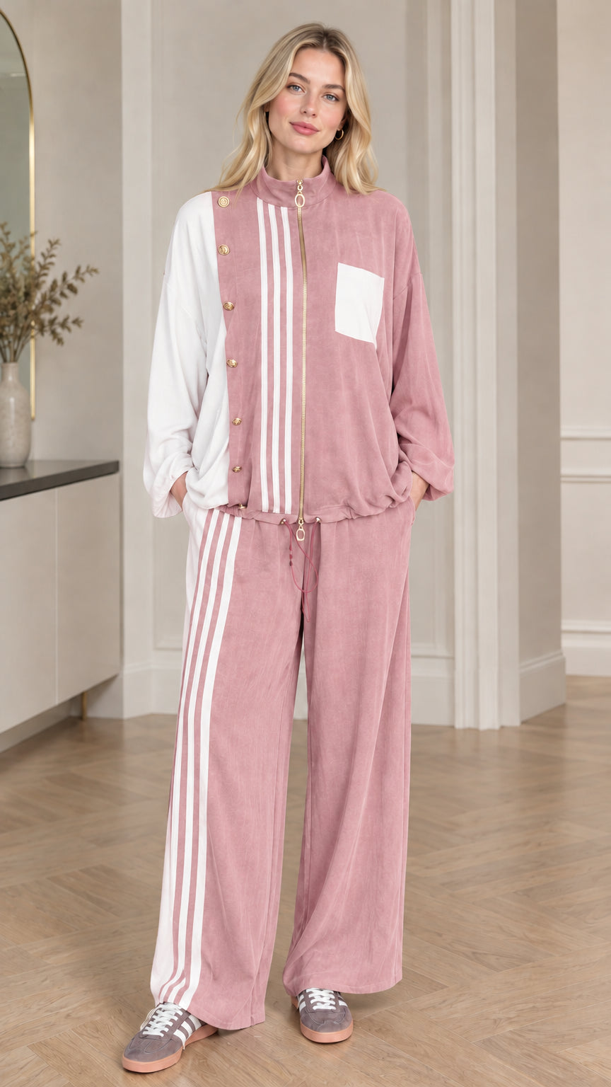 Full-body view of woman wearing dusty pink and white colorblock tracksuit set