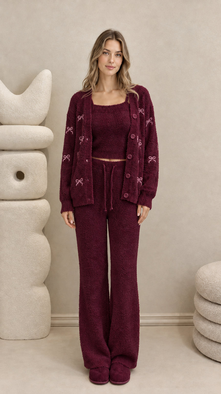 Model wearing burgundy 3-piece plush knit lounge set with pink embroidered bows
