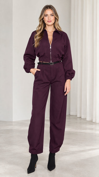 Front view of model wearing burgundy long sleeve zip front utility jumpsuit with black belt