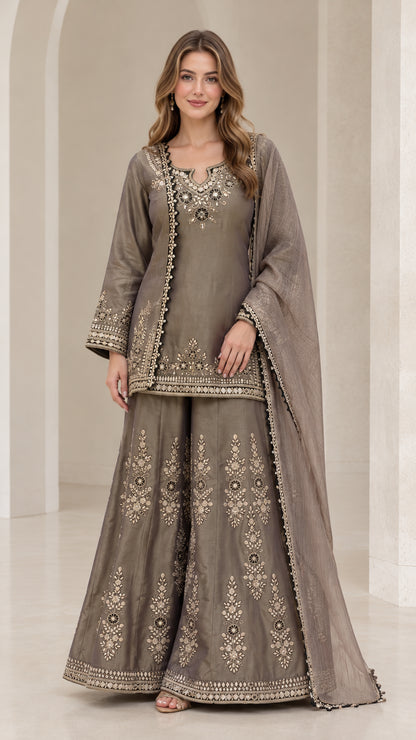 Front view of woman wearing taupe grey embroidered kurti sharara suit set with dupatta