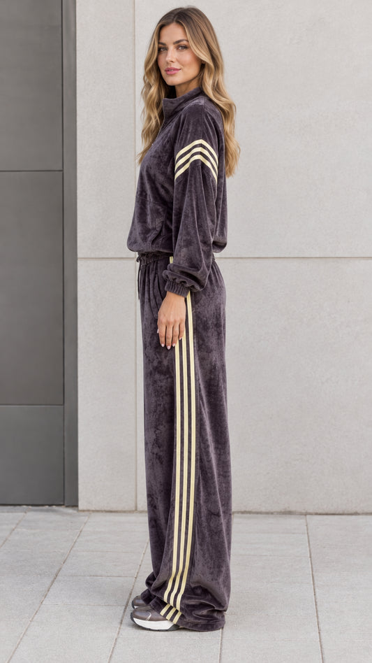 Side profile view of model in charcoal grey plush velour tracksuit showing contrast side stripes