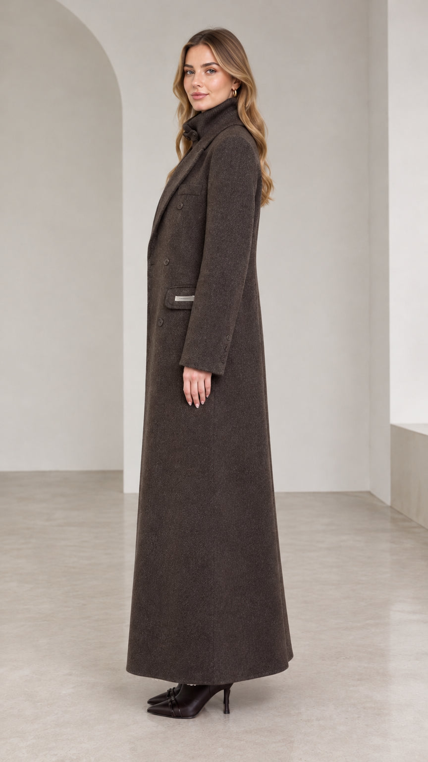 Side profile of woman modeling tailored dark brown maxi overcoat