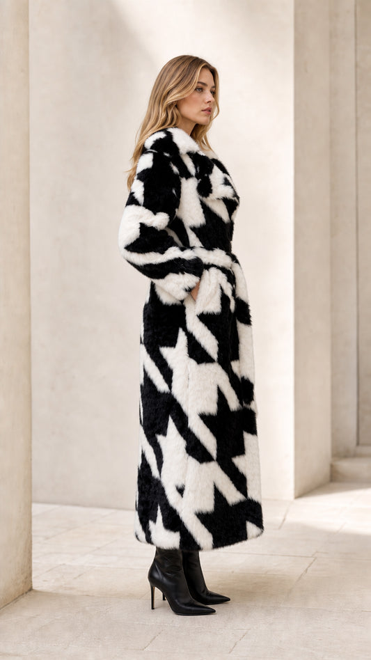 Side profile view of woman wearing long black and white houndstooth faux fur wrap coat