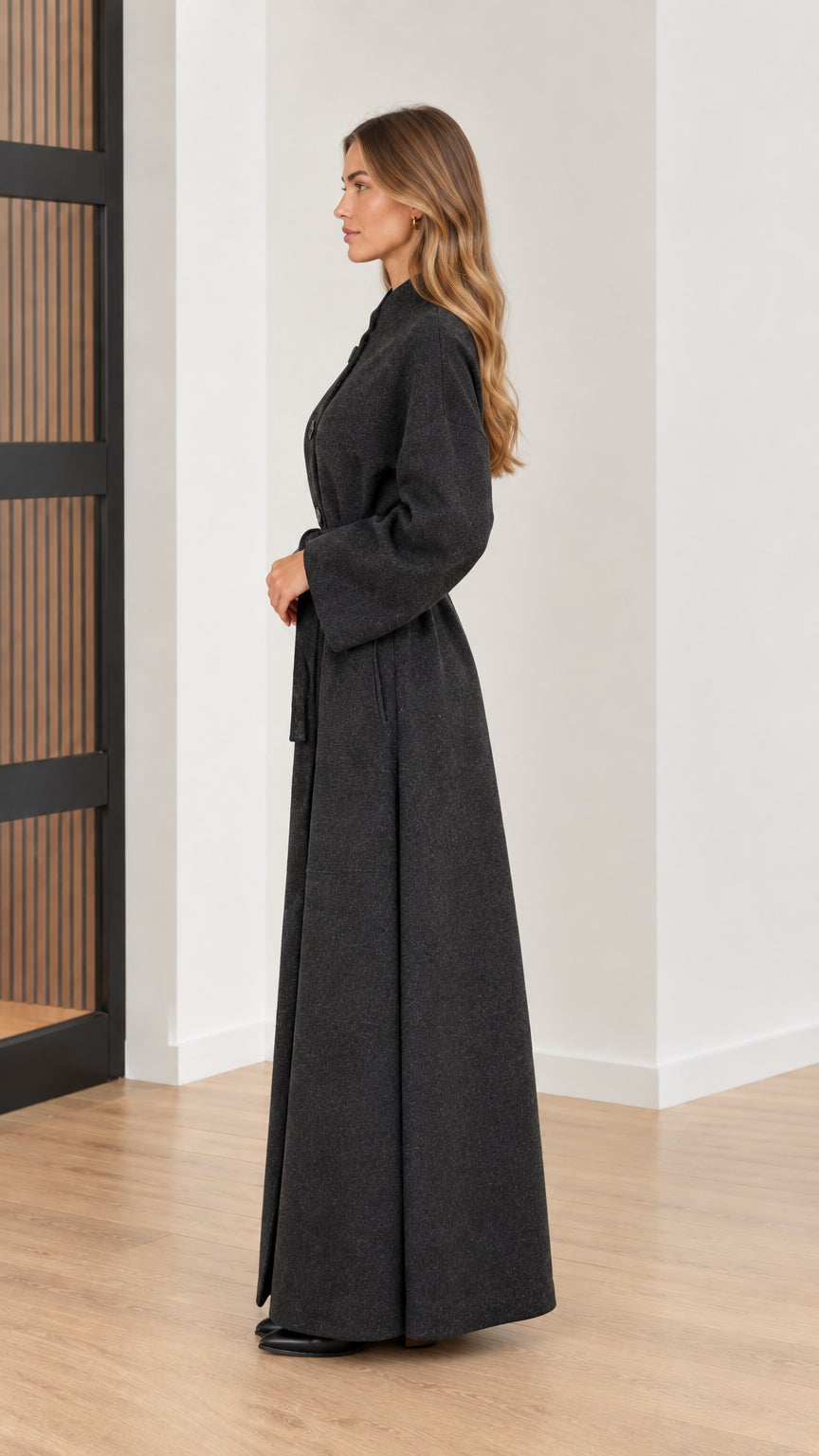 Side profile view of woman in long charcoal grey wool-look overcoat