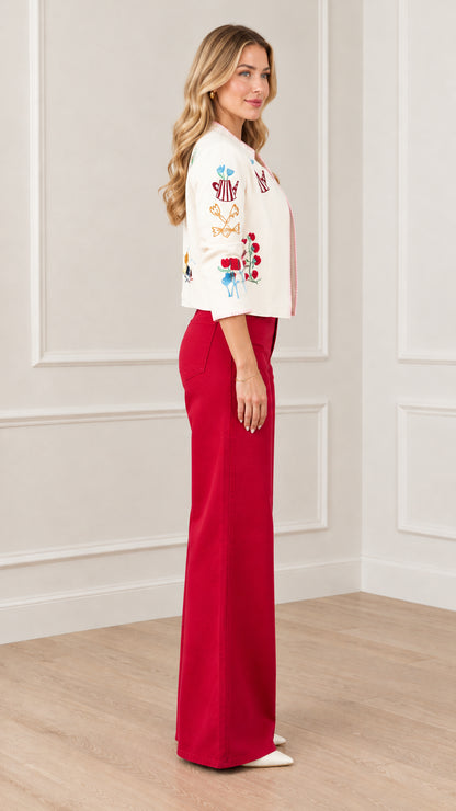 Side profile view of cream whimsical embroidered cropped jacket