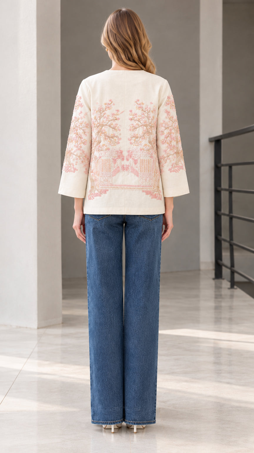 Back view of model wearing cream embroidered jacket showing floral pattern
