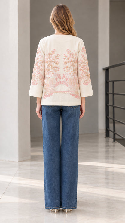 Back view of model wearing cream embroidered jacket showing floral pattern