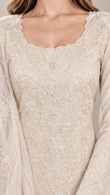 Close-up detail of champagne floral embroidery, beadwork, and scalloped neckline