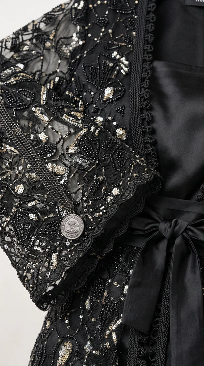Close-up detail of black sequin embellishments, floral lace embroidery, cuff button, and satin tie