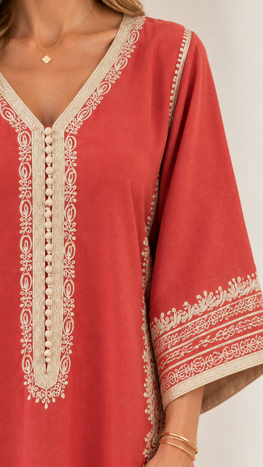 Close-up of V-neckline and intricate contrast embroidery on rust red kaftan