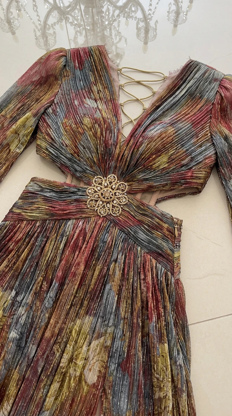 Close-up flat lay of metallic plissé bodice, ornate floral brooch, cutouts, and back ties