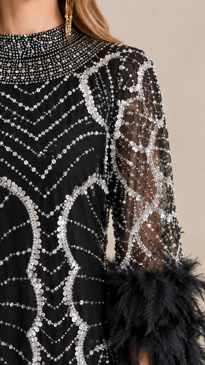 Close-up detail of silver sequin patterns, beaded neckline, and black feather cuffs