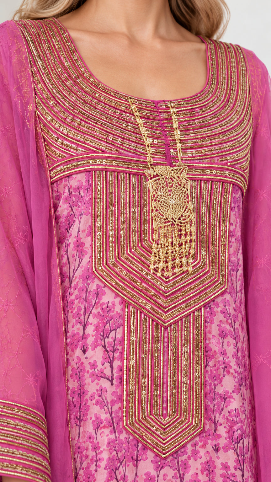 Close-up detail of gold embroidered bib and neckline on fuchsia floral fabric