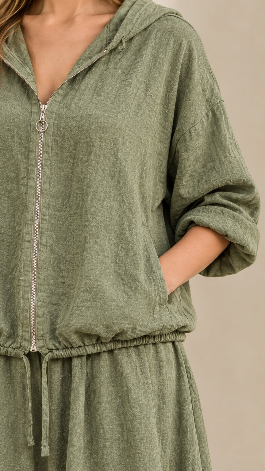 Close-up detail of zipper, hood, and drawstring hem on sage green textured set