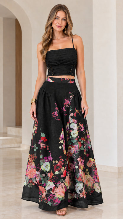 Full-length view of black floral ruched crop top and flowing maxi skirt set