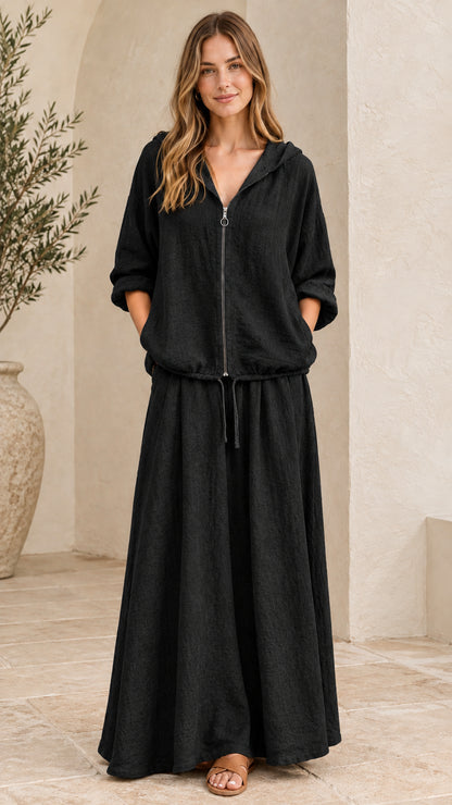 Front view of woman wearing black hooded zip-up top and maxi skirt set