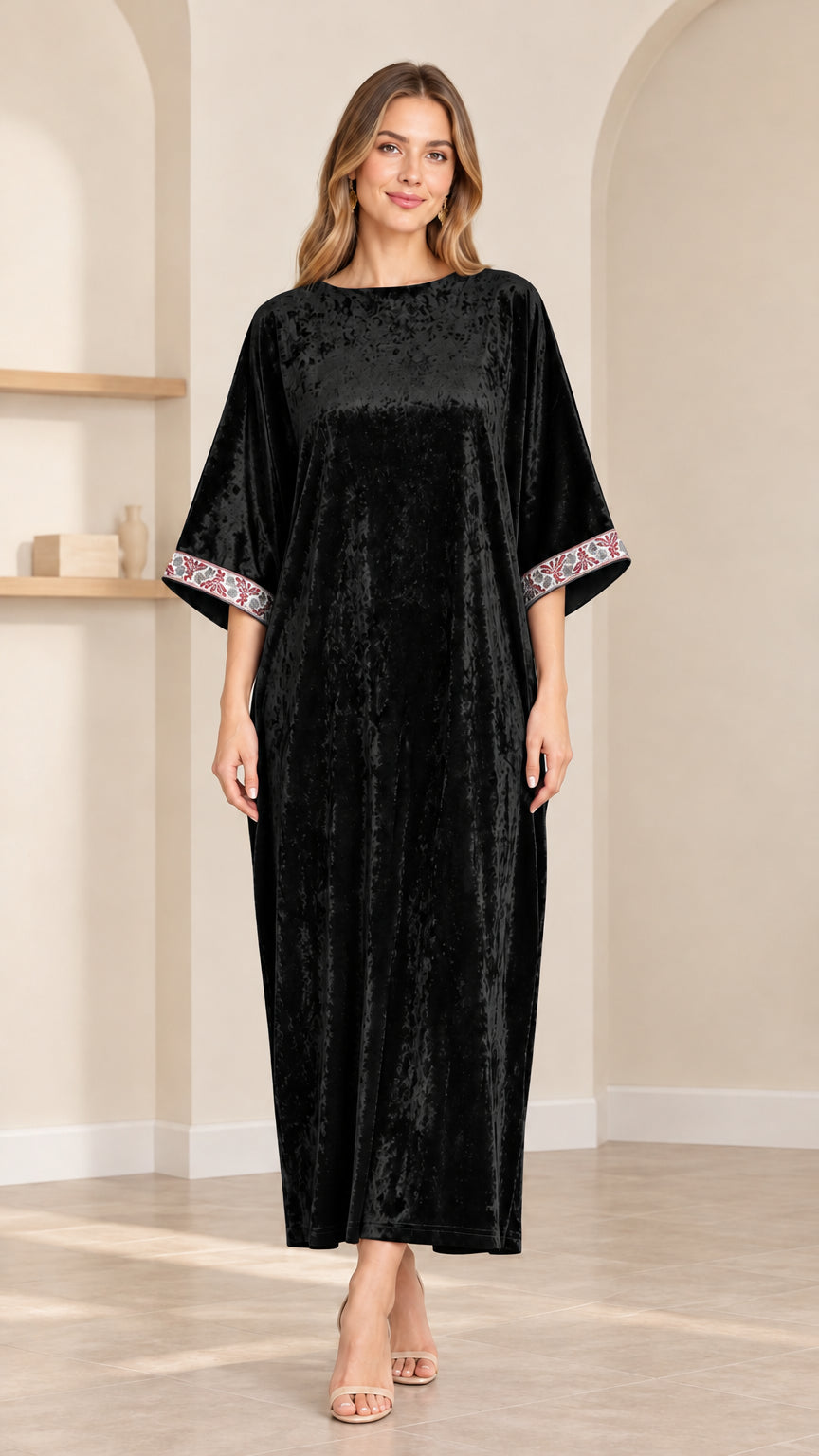 Front view of model wearing black crushed velvet kaftan maxi dress with embroidered cuffs