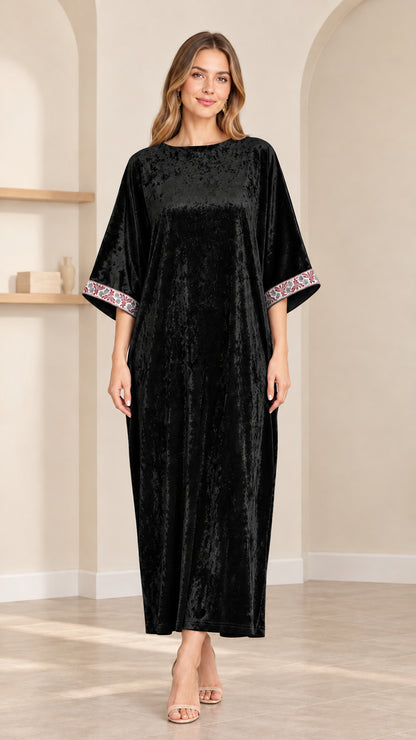 Front view of model wearing black crushed velvet kaftan maxi dress with embroidered cuffs