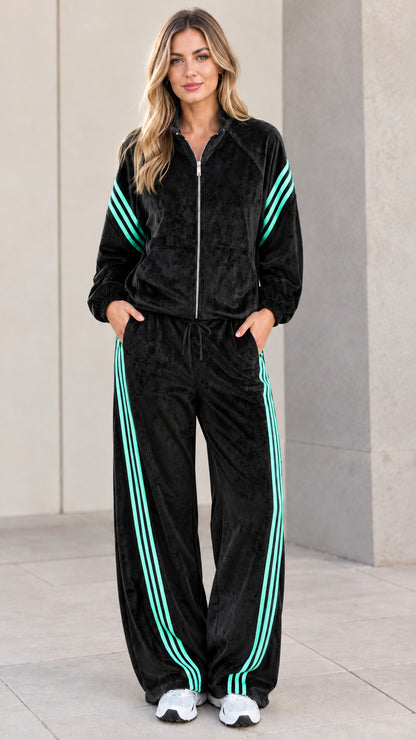 Model wearing black velour tracksuit set with mint contrast stripes