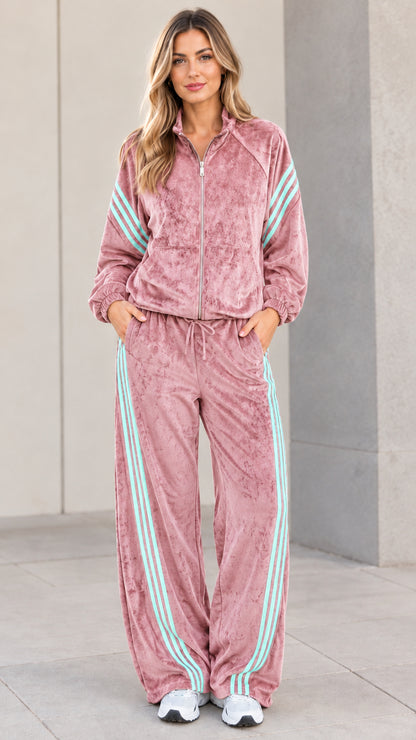Model wearing dusty pink velour tracksuit set with contrast stripes