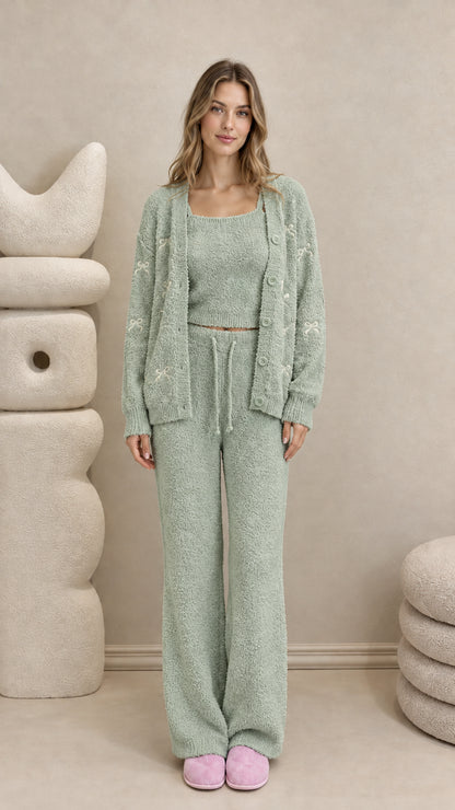 Model wearing sage green 3-piece fuzzy knit lounge set with embroidered bows