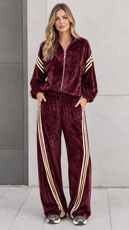 Front view of model wearing deep burgundy red velour tracksuit set with cream athletic stripes