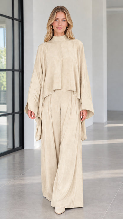 Front view of champagne cream draped mock neck cape top and matching trousers set