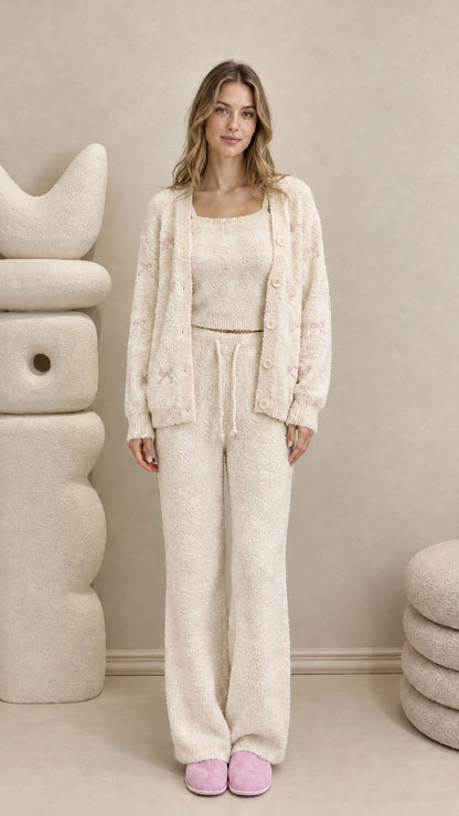 Model wearing cream off-white 3-piece fuzzy knit lounge set with embroidered bows